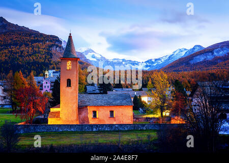 Old christianity church in Sils village (near lake Sils) in Swiss Alps. Red light on building and snowy mountains on background. Switzerland, Maloja region, Upper Engadine. Landscape photography Stock Photo