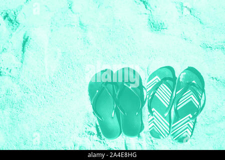Summer slippers. Flip flop on sand beach background in mint color. Copy space, top view. Trendy green and turquoise color. Holiday, vacation and trave Stock Photo
