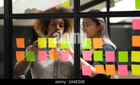 Diverse business women writing plan and ideas using sticky notes Stock Photo