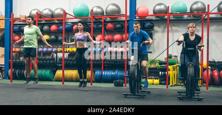 Athletes doing air bike and skipping rope Stock Photo