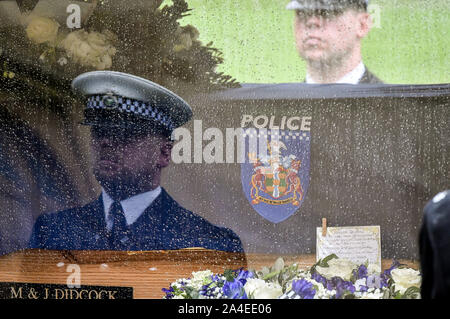 A police is reflected in hearse window by the coffin of PC Andrew Harper, the Thames Valley Police officer who died from multiple injuries after being dragged under a van while responding to reports of a burglary, as the cortege leaves the quadrangle at Christ Church Cathedral in St Aldate's, Oxford. Stock Photo