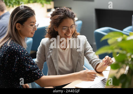 Women colleagues using computer working together in co-working space Stock Photo