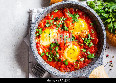 Traditional shakshuka in a pan. Fried eggs in tomato sauce with herbs, copy space. Stock Photo