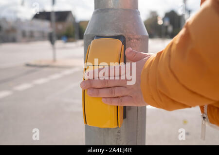Woman presses a finger on the button for crossing the road Stock Photo