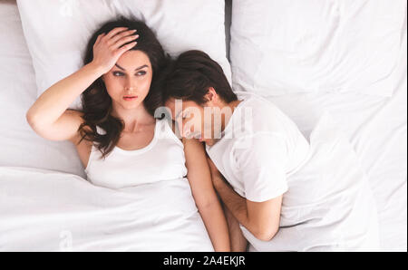 Grumpy woman with insomnia lying with man in bed Stock Photo