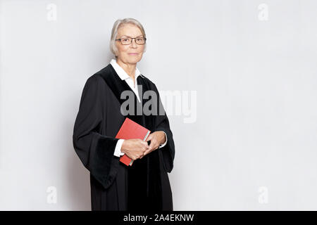 Female jurisdiction concept: friendly german judge in a black judge's gown holding a book with the constitutional text. Stock Photo
