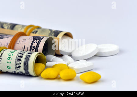 Dollar rolled up with pills flowing out isolated on white background, high costs of expensive medication concept. Copy space. Stock Photo
