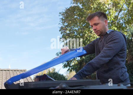 Caucasian man throwing a paper into a blue plastic garbage bin. Stock Photo