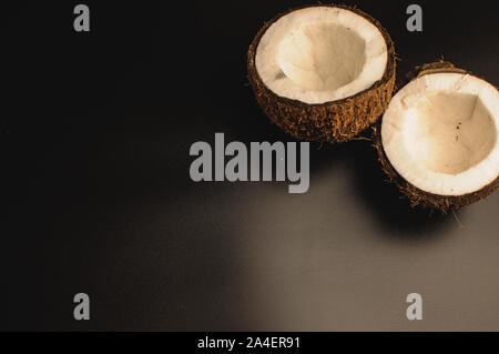 ugly organic coconut on a black background, isolate. a broken nut in a shell the white insides of a coconut, which began to decompose and covered with Stock Photo