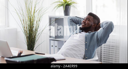 Black employee resting from office work, leaning back on chair Stock Photo