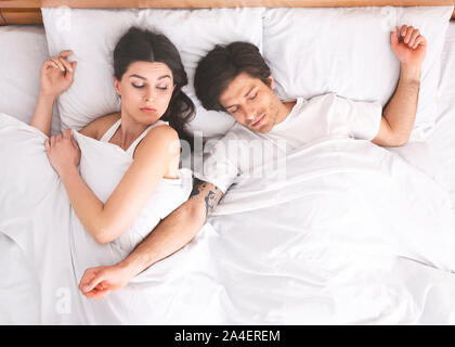 Young woman suffering from her sprawled man in bed Stock Photo