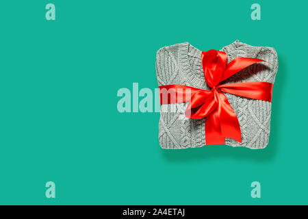 New Year or Christmas top view holiday celebration red ribbon packing knitted sweater as present or gift copy space green color background.Template Stock Photo