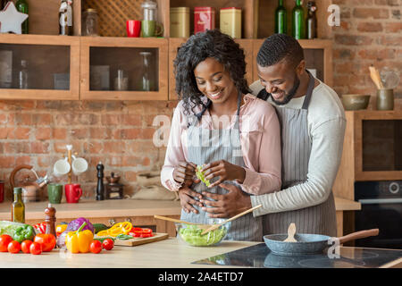 Husband hugging his wife from behind while cooking Stock Photo
