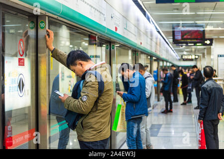 Passsengers watching Cellphones in the Subway station in Beijing, China. Stock Photo