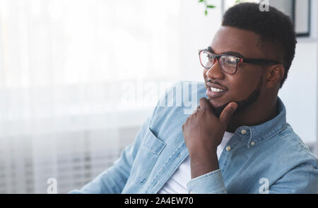 Confident black man in glasses touching his beard in office Stock Photo