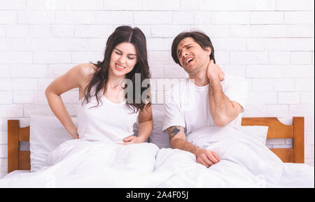 Young sad couple waking up, suffering from back and neck ache Stock Photo