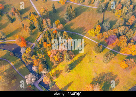 Aerial view flight over autumn valley park with meadows and a winding river with bridge, bright trees Stock Photo