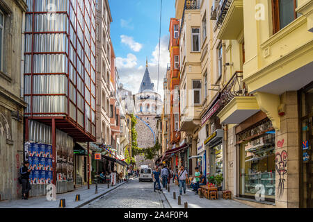 The historic Galata Tower rises in the distance behind a typical Turkish street with markets and shops in Istanbul, Turkey Stock Photo