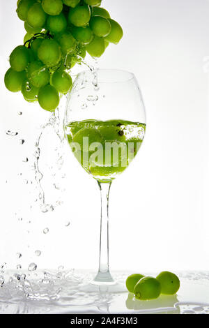 Green grape with water splash into glass. White background Stock Photo