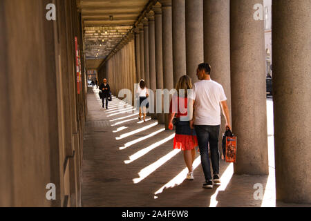 Long colonnade in baroque style with people walking with shopping bags. Afternoon sun with long shadows. Copenhagen, Denmark - April 29, 2019 Stock Photo