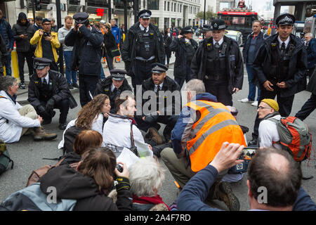 London, UK. 14 October, 2019. Police officers serve notices under Section 14 of the Public Order Act 1986 to climate activists from Scientists for Extinction Rebellion who had blocked the busy junction at King William Street in front of London Bridge on the eighth day of International Rebellion protests across London. Today’s activities were concentrated around the  City of London’s finance district. Credit: Mark Kerrison/Alamy Live News