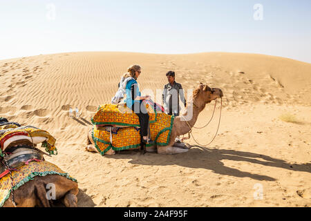 A camel driver instructing a tourist on how to ride a camel, Thar Desert, Rajasthan, India. Stock Photo