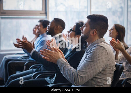 Business conference. Colleagues clapping hands to speaker Stock Photo