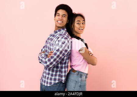 Happy young couple standing back to back and smiling Stock Photo