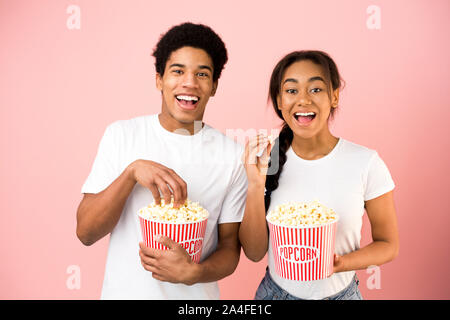 African-american couple eating popcorn and watching comedy film Stock Photo
