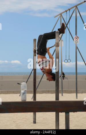 Venice Beach, California - A male gymnast in dorsal grip on the uneven bars, public exercise on Venice beach Stock Photo