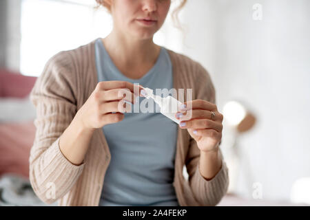Young woman using nasal spray while suffering from cold Stock Photo
