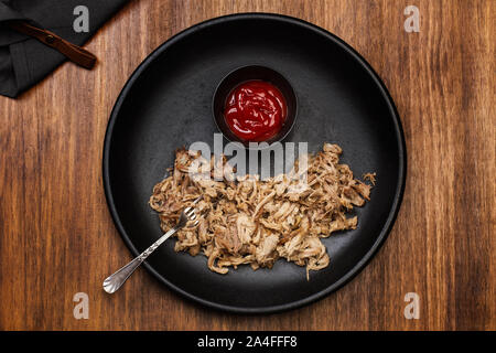 Pulled pork in a black plate on a wooden table Stock Photo
