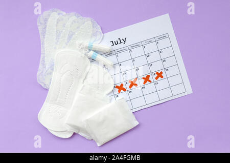 Aspects of women wellness in monthlies period. Menstrual pads and tampons on menstruation period calendar. Woman critical days, gynecological menstrua Stock Photo