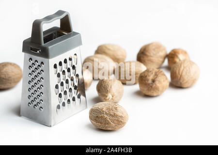 A little grater with nutmegs on a white background Stock Photo