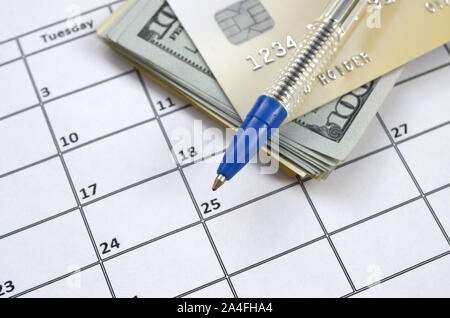 Pen and credit card on many hundred US dollar bills on calendar page close up. Business and financial planning concept. Accountant work Stock Photo