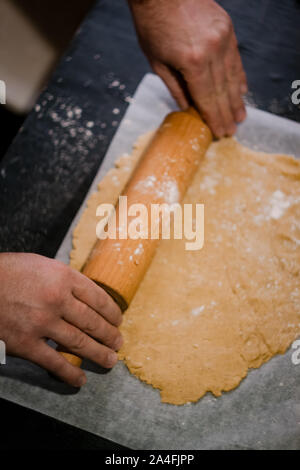 baker's hands roll ginger dough on a dark background. Close-up, soft focus. Side view, top view. Copy space. Stock Photo