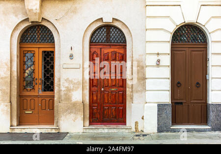 Three old wooden arched doors decorated with iron door knockers and molding. Vintage entry doors in Valletta, Malta. Stock Photo