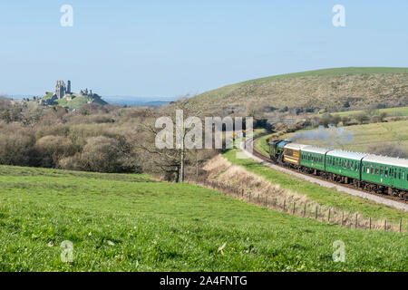 Railway and coach pass the Corfe Castle in Dorset, UK Stock Photo