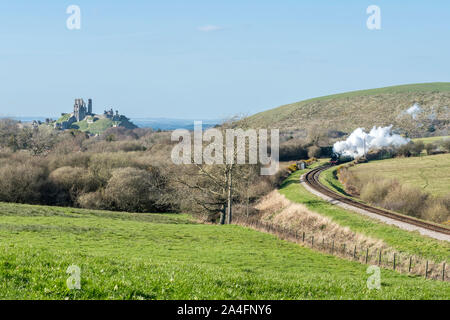 Railway and coach pass the Corfe Castle in Dorset, UK Stock Photo