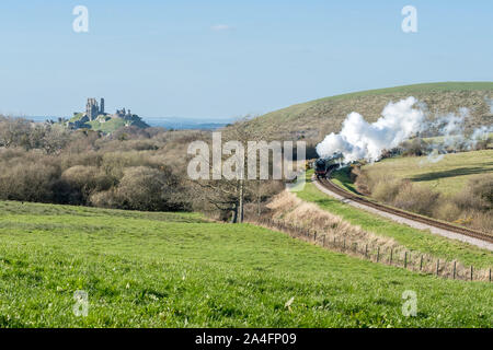 Railway and coach pass the Corfe Castle in Dorset, UK Stock Photo