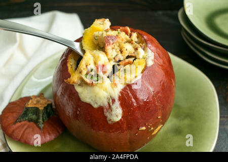 Baked pumpkin stuffed with a mixture of bread, cheese, bacon, and herbs and baked until the filling has melted Stock Photo