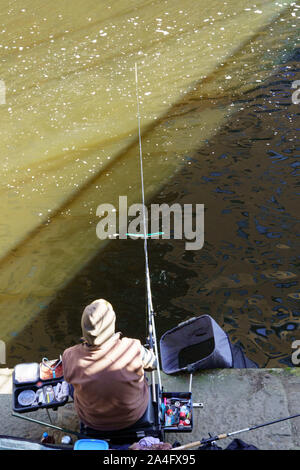 A man fishing on a canal with a long fishing rod, Bridgewater Canal, Manchester, Greater Manchester, England, UK. Stock Photo