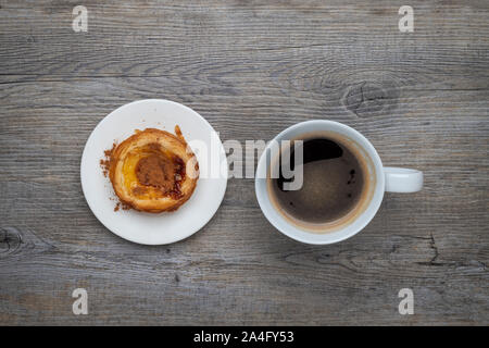 Traditional Portuguese Pastel de Nata tart with a cup of black coffee on a wooden table Stock Photo