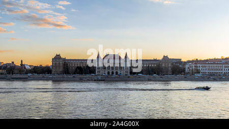 A boat driving by the Budapest University of Technology and Economics during sunset. Stock Photo
