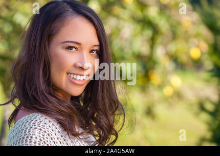 Beautiful happy Asian Eurasian Chinese biracial young woman or girl outdoor smiling portrait in summer sunshine Stock Photo