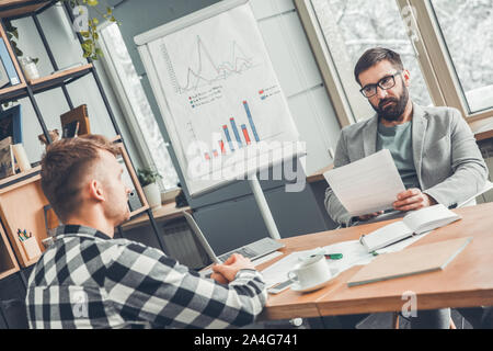 Male startupers working together at office sitting looking at each other serious Stock Photo