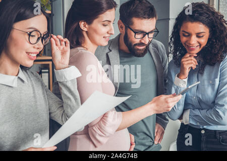 Startupers working together at office standing pregnant woman watching video on digital tablet smiling happy close-up Stock Photo