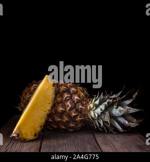Sliced pineapple on old rustic desk Black background. Stock Photo