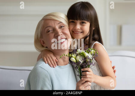 Head shot portrait happy grandmother embracing little cute granddaughter. Stock Photo