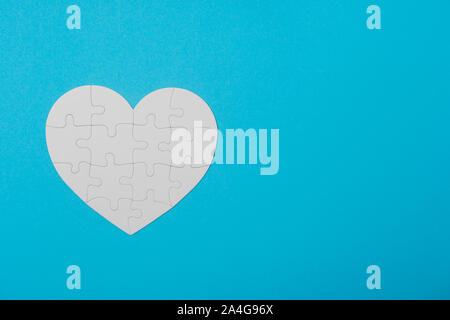 White Puzzle Heart Shape On Blue background Stock Photo